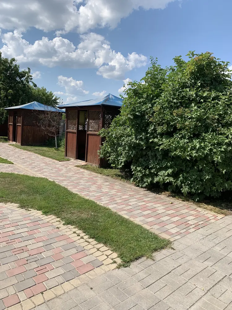 Брукована доріжка до бесідок серед кущів і дерев